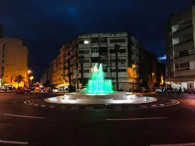 a fountain in the middle of a street at night at budget holidays room in Casablanca