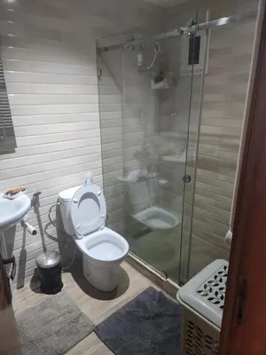 a bathroom with a toilet and a glass shower at Joumaira appartement Beach in Rabat