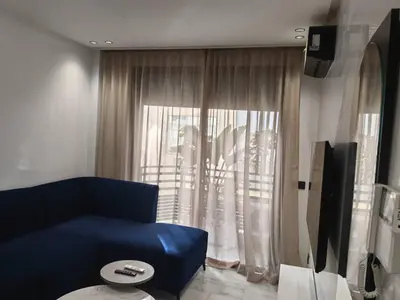 a living room with a blue couch and a window at Abbogroup Appartement 2 in Casablanca