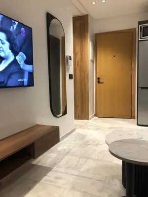 a room with a tv on the wall and a table at Abbogroup Appartement 2 in Casablanca