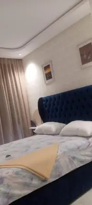 a bed with a blue headboard in a bedroom at Abbogroup Appartement 2 in Casablanca