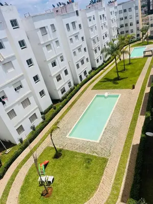 an apartment with a swimming pool in front of a building at Jannat tamaris in Tamaris
