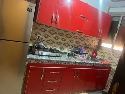 a red kitchen with a sink and red cabinets at Appartement a settat in Settat
