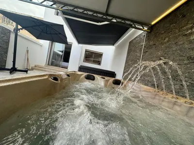 a hot tub with a water feature with an umbrella at RÉSIDENCE LE BIjOU DE L'AGDAL in Rabat