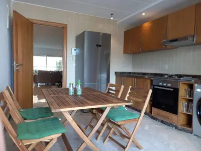 a kitchen with a wooden table and chairs at Peninsula Dar Bouazza in Tamaris