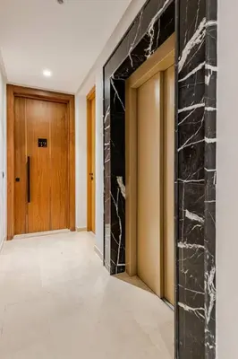 a hallway with a stone wall and a wooden door at Appartement de luxe - Les Princesses avec Parking in Casablanca