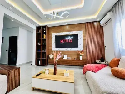 a living room with a television on a wall at Elegant 3BR Stay 5min to Hay Riad in Temara