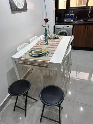 a white table with two black chairs and a kitchen at Elegant 3BR Stay 5min to Hay Riad in Temara