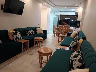 a living room with green couches and a kitchen at Bati d or in Mohammedia