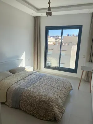 a bedroom with a bed and a large window at Bel Appartement à Harhoura pour les familles in El Harhoura