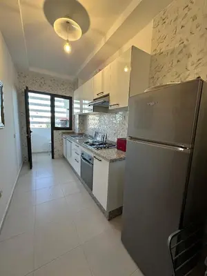 a kitchen with a stainless steel refrigerator and white cabinets at Bel Appartement à Harhoura pour les familles in El Harhoura