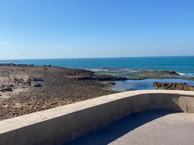 a stone bench sitting on a beach near the ocean at Bel Appartement à Harhoura pour les familles in El Harhoura