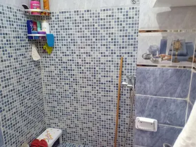 a bathroom with a blue tiled shower with a toilet at confy house in Casablanca