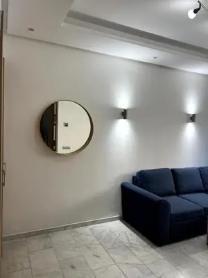 a living room with a blue couch and a mirror at 1 bed apt In Prestigia hay Riad rabat in Rabat