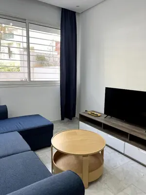 a living room with a blue couch and a tv at 1 bed apt In Prestigia hay Riad rabat in Rabat