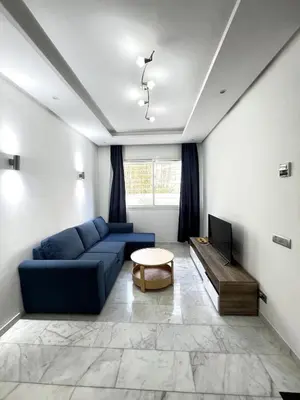 a living room with a blue couch and a tv at 1 bed apt In Prestigia hay Riad rabat in Rabat