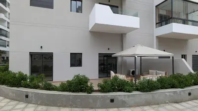 a white building with a table and an umbrella at Appt neuf Zenata- 2 chambres et Mezzanine - Piscine in Aïn Harrouda