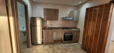 a small kitchen with a refrigerator and a sink at Appartement ALAA - Malaga beach in Mansouria
