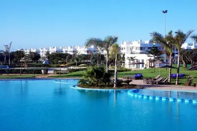 a large pool of blue water with buildings in the background at Eden Island Villa - Bouznika in Bouznika
