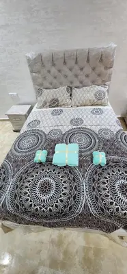 a bed with a black and white comforter on it at Appartement Alaa in Mansouria