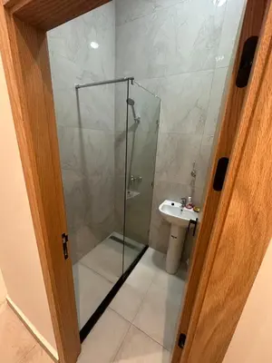 a bathroom with a glass shower and a sink at زنقة توبقال أكدال عمارة 24 رقم 3 in Rabat
