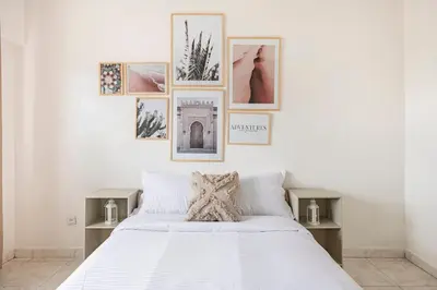 a bedroom with a white bed with pictures on the wall at Spacious 2Bedrooms Fully equipped-5min Agdal Station in Rabat