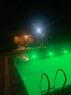 a swimming pool at night with green lights at Magnifique Chalet en bois collé à la forêt de Benslimane in O Ben Slimane