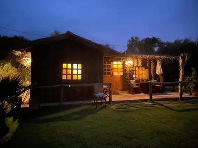 a small house with a patio at night at Magnifique Chalet en bois collé à la forêt de Benslimane in O Ben Slimane