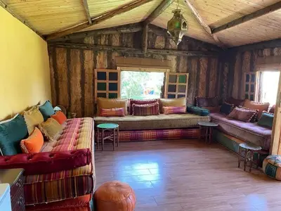 a living room with couches and a window at Magnifique Chalet en bois collé à la forêt de Benslimane in O Ben Slimane