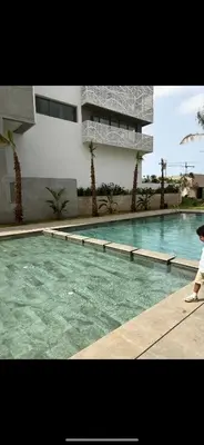 a person standing next to a swimming pool with a building at Appartement, Casablanca in Casablanca