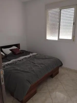 a bedroom with a bed and a window with blinds at résidence les perles de Bouznika in Bouznika