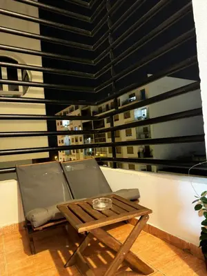 a table and a chair on a balcony with a window at SUITOUISS - Agdal 2 - Appartements à 2 minutes de la gare de train TGV Rabat in Rabat