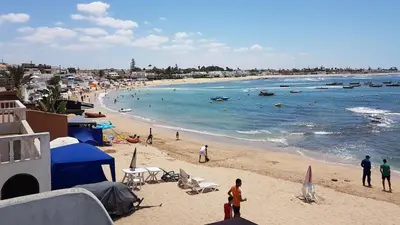 a beach with people on the sand and the water at Beautiful Apartment with Seaside Pool in Mansouria
