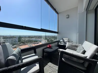 a balcony with two chairs and a large window at Appartement Miramar vue panoramique Mohammedia in Mohammedia