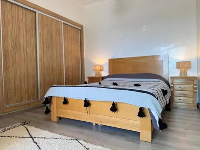 a bedroom with a bed with a wooden headboard at Appartement Miramar vue panoramique Mohammedia in Mohammedia