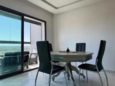 a table and chairs in a room with a view at Appartement Miramar vue panoramique Mohammedia in Mohammedia