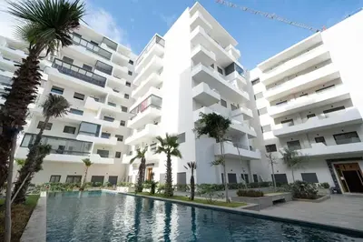 an apartment building with a swimming pool and palm trees at Premium Romantic 1 Bedroom & Living Room with Swimming pool & Garden view in Casablanca
