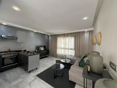 a large living room with a couch and a kitchen at Appartement luxueux au bord du mer in Casablanca