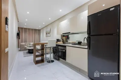 a kitchen with a black refrigerator and a living room at Acacia Studio 09 in Casablanca