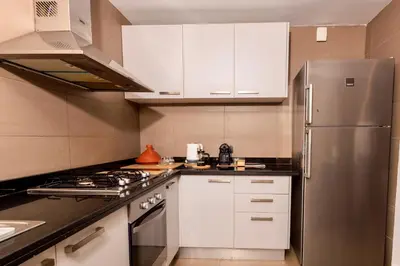 a kitchen with white cabinets and a stainless steel refrigerator at Beyti in Rabat