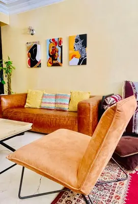 a living room with a brown couch and some paintings at Top Location Apartment City Center 1min Away From Tram Station in Casablanca