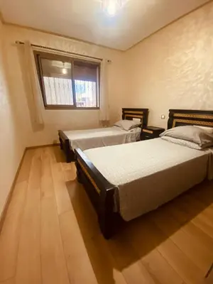 a bedroom with two beds and a window at Charmant appartement joyau du parc 200m plage in Mohammedia