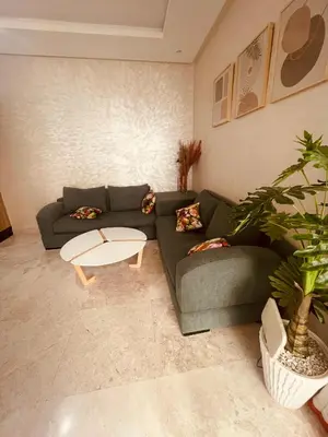 a living room with a green couch and a table at Charmant appartement joyau du parc 200m plage in Mohammedia