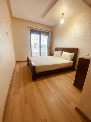 a bedroom with a bed and a large window at Charmant appartement joyau du parc 200m plage in Mohammedia