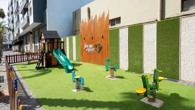 a playground with play equipment on the grass at Charmant appartement joyau du parc 200m plage in Mohammedia