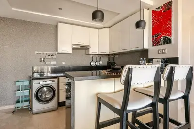 a kitchen with white cabinets and a washing machine at Appartement de Luxe - Piscine et Accès à la Plage in Bouznika