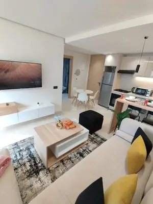 a living room with a white couch and a kitchen at Residence La Reine II 24H Reception Cosy & Central Apartment 1 Minute Near To MOHAMMED V SPORTS COMPLEX 5 Min By Car To Ain Diab Corniche With Optical Fiber Wifi Casablanca in Casablanca