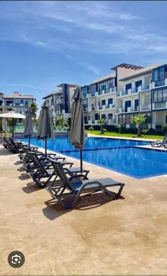 a row of lounge chairs with umbrellas next to a swimming pool at Appartement Les Crêtes in Casablanca