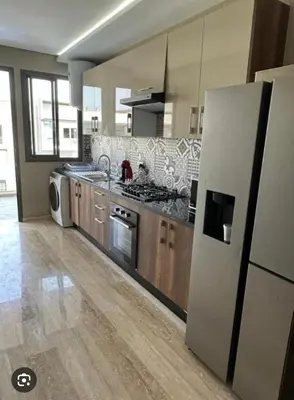 a large kitchen with a refrigerator and a stove at Appartement Les Crêtes in Casablanca