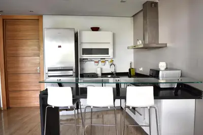 a kitchen with a counter with white chairs in it at Le Sacré-Coeur - by Mi-Haven in Casablanca